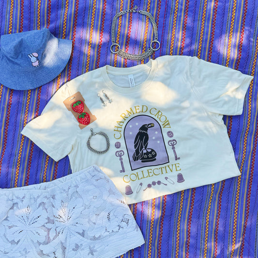 Light blue t-shirt, shorts, and hat on a striped purple blanket outdoors