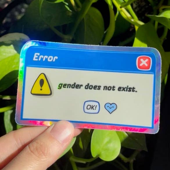Vinyl sticker with 'Error: gender does not exist' text held in front of green leaves