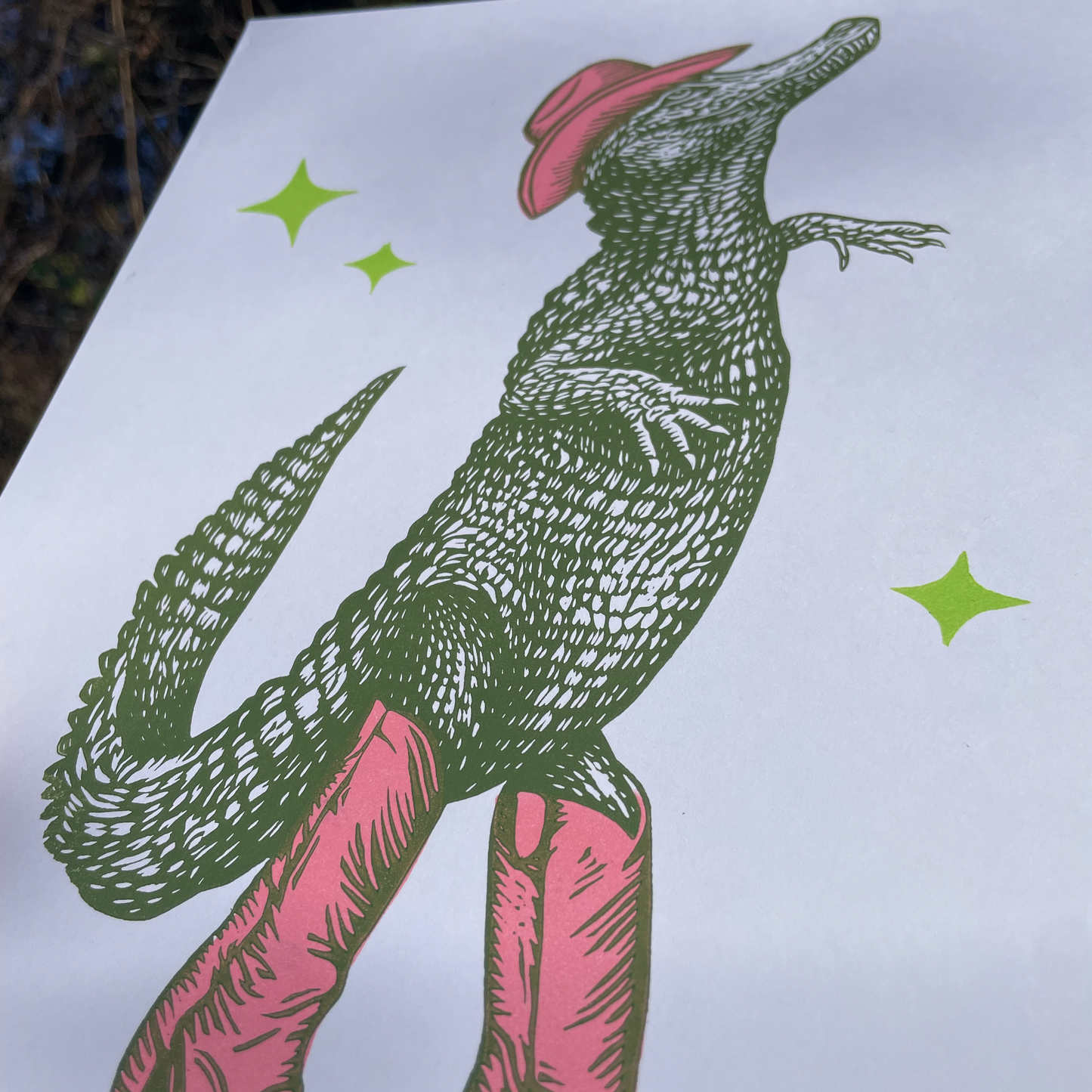 Illustration of a crocodile wearing pink boots and a hat on a white background with green stars.