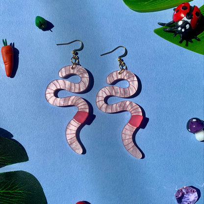 Worm earrings on a blue background with decorative elements.