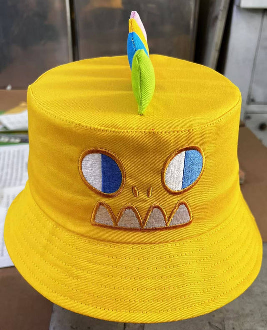 Yellow bucket hat with a cartoon face design on a flat surface.