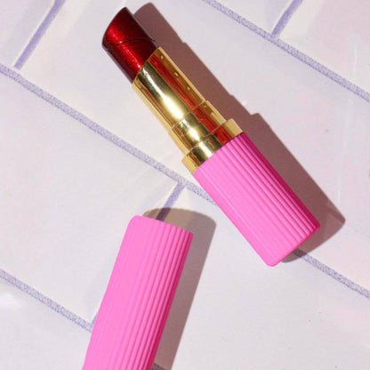 Pink lipstick lighter with gold cap on a tiled surface