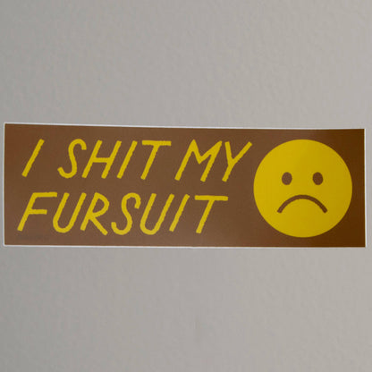 Sticker with text 'I SHIT MY FURSUIT' and a sad face on a gray background