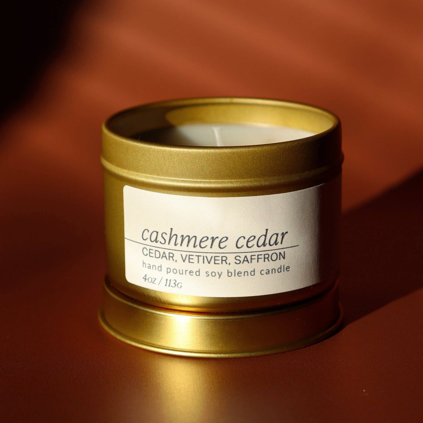 Gold candle container with 'cashmere cedar' label on a brown background