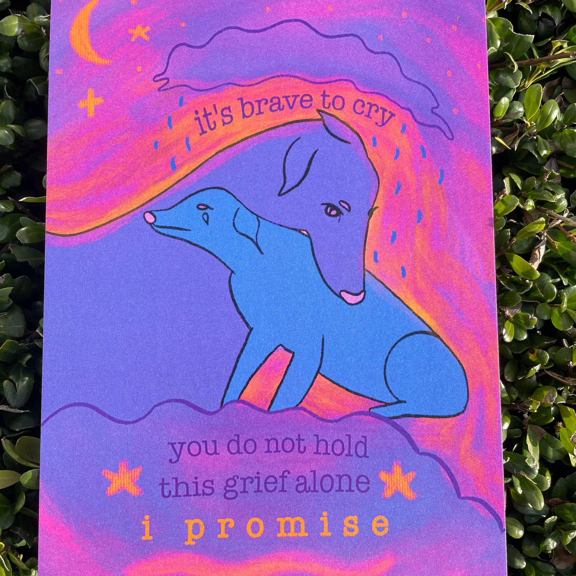 Card with a blue dog illustration and text that reads "It's brave to cry. You do not hold this grief alone. I promise" on a green foliage background