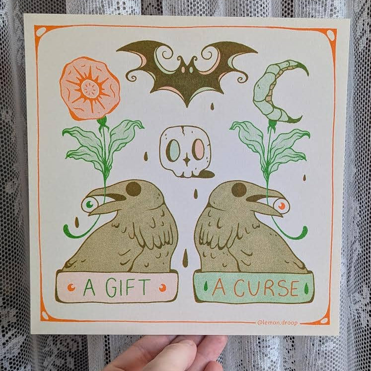 Illustrated card with raven and flower symbols labeled 'A Gift' and 'A Curse' held against a lace curtain background.