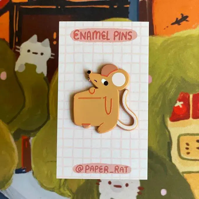 Enamel pin of a cartoon mouse on a white card with grid lines, surrounded by colorful illustrations.