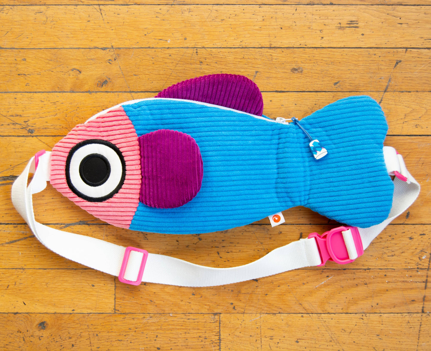 Colorful fish-shaped bag with a strap on a wooden floor
