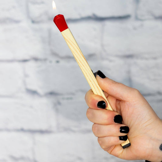 Hand holding a matchstick shaped lighter against a textured gray background