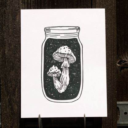 Linocut print of mushrooms inside a mason jar on a white background