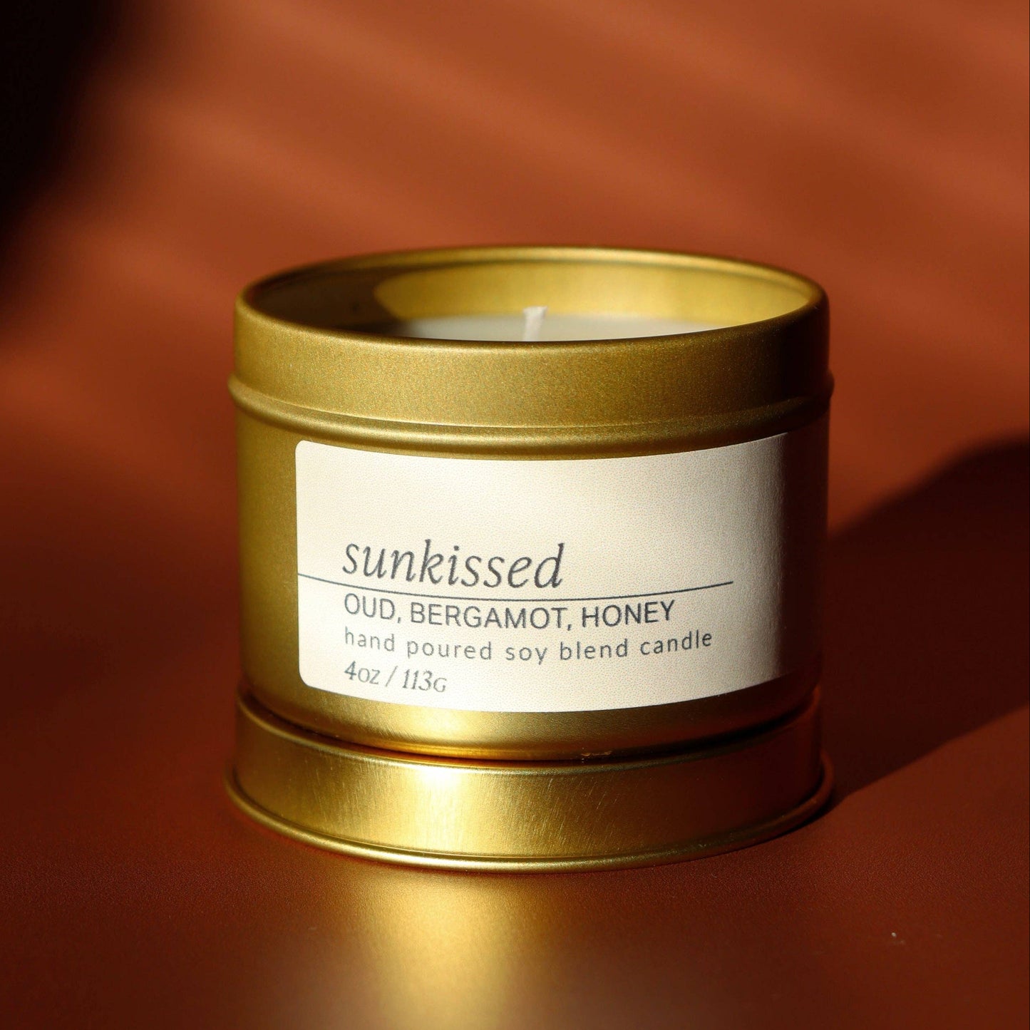 Candle in a gold tin with a label on a brown background